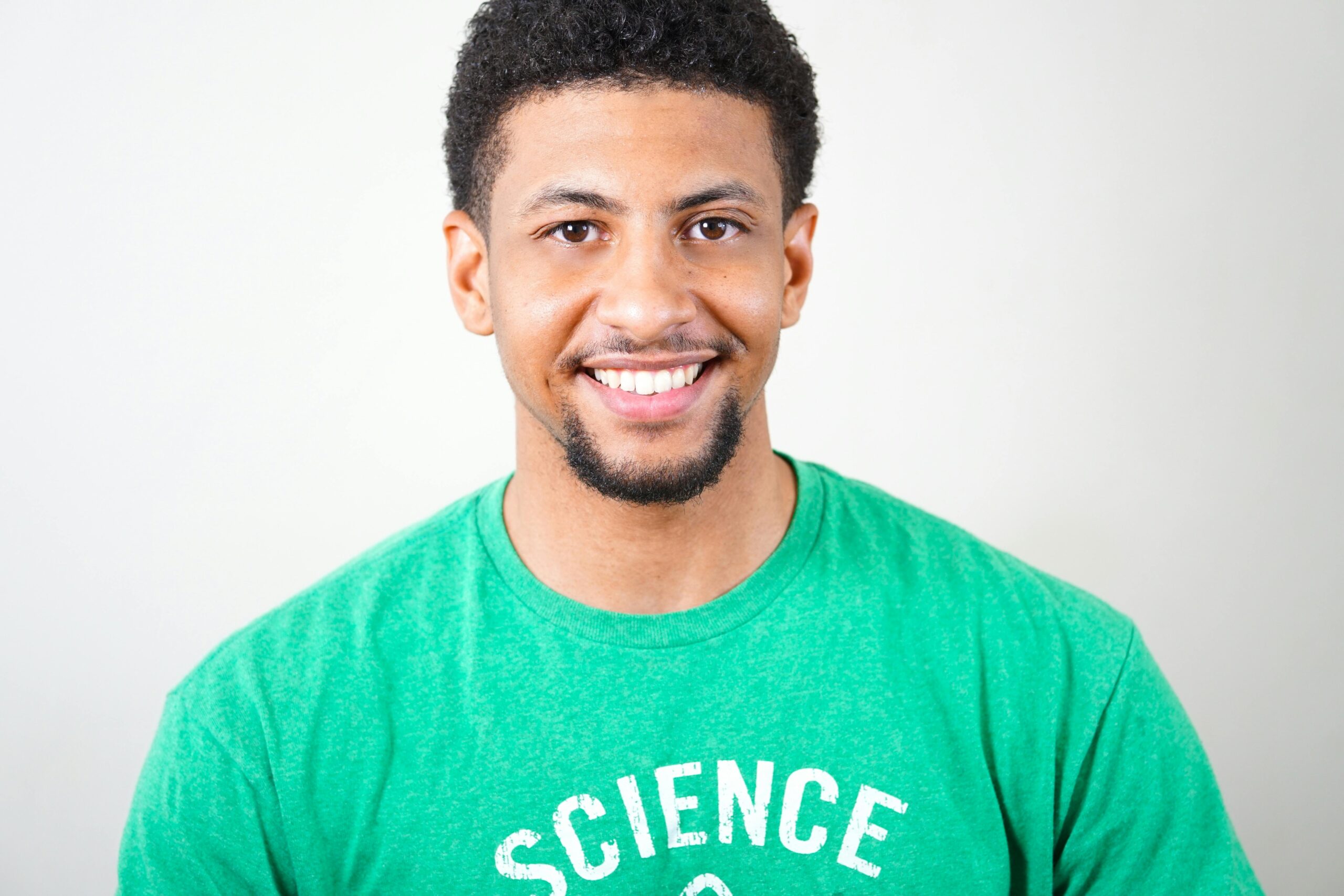 Home Portrait of a smiling young man wearing a green T-shirt with science text.